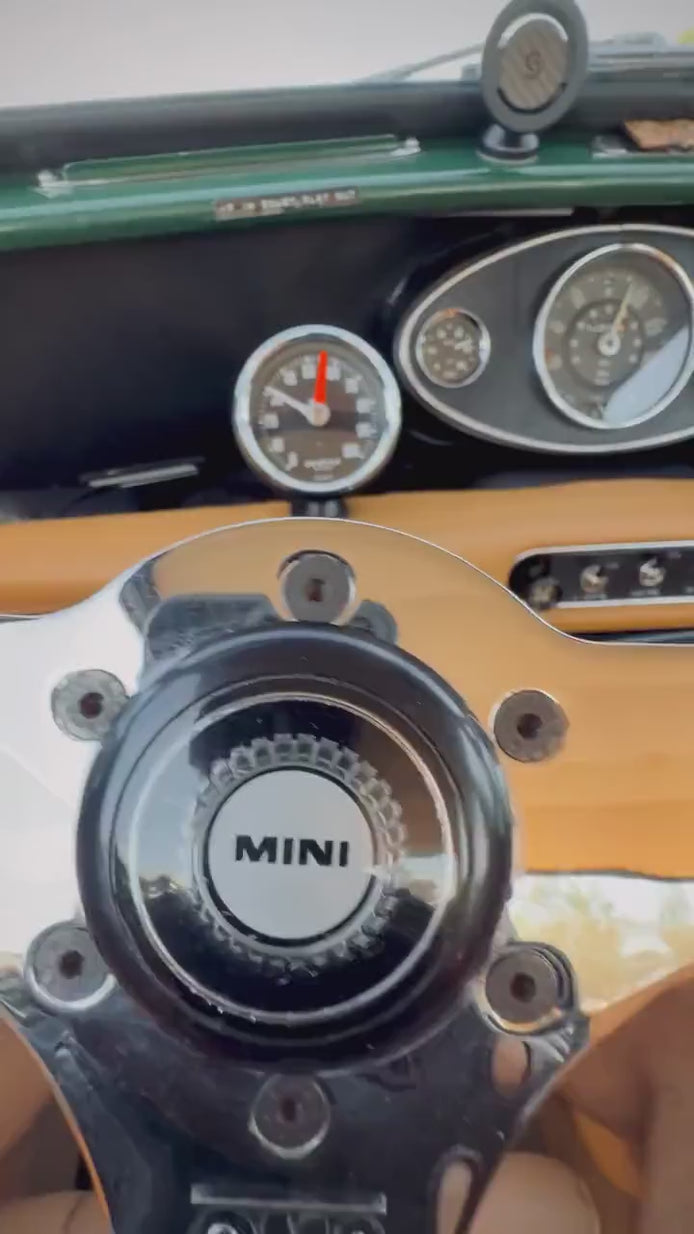 Gants de conduite Targa portés au volant d'une mini cooper vintage avec un volant en bois sur la route ensoleillée 